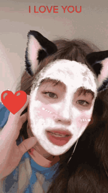 a girl with cat ears and a white mask on her face holds a red heart and says " i love you "