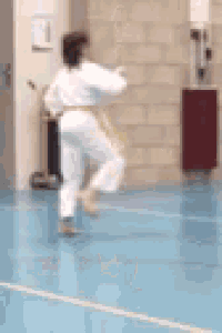 a person in a white karate uniform with a yellow belt is standing on one leg