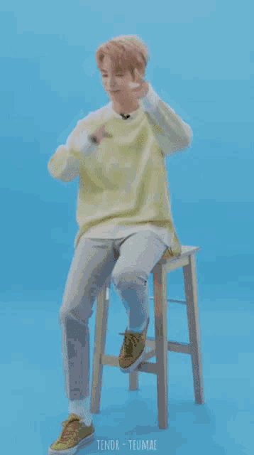 a boy is sitting on a stool with a blue circle around his head and the word teumae on the bottom right