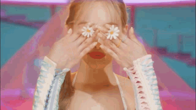 a close up of a woman covering her eyes with flowers .