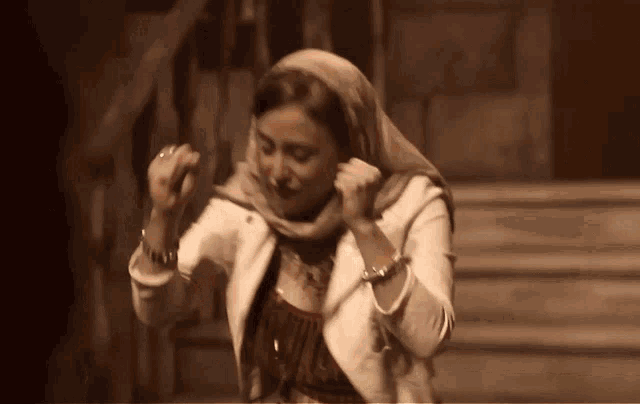 a woman wearing a scarf and a white jacket dancing