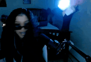 a woman wearing sunglasses is sitting in front of a microphone .