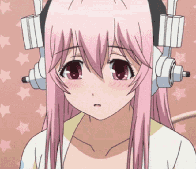 a girl with pink hair and headphones on her head looks at the camera