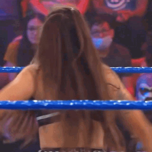 two women are wrestling in a ring with a referee and a crowd watching
