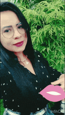 a woman wearing glasses and a black shirt is holding a pink balloon with a kiss on it