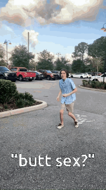 a boy in a blue shirt is running in a parking lot with the words " butt sex " written on it