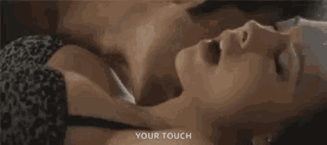 a man is touching a woman 's neck while they are laying on a bed .
