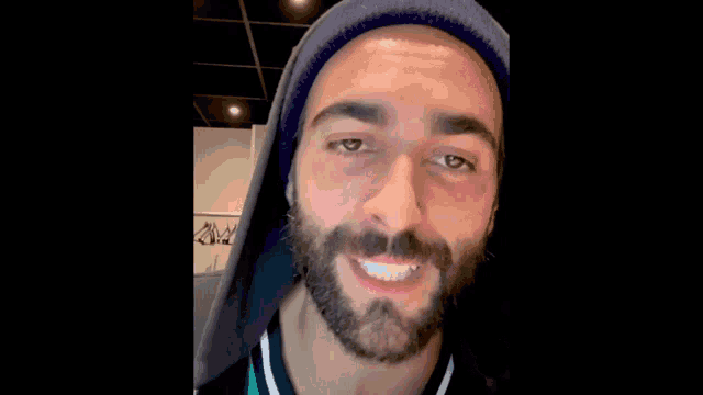a man with a beard is wearing a hooded jacket