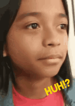 a close up of a young girl 's face with the words huh written on it