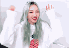 a woman with long green hair is wearing a white sweatshirt and a crown on her head .