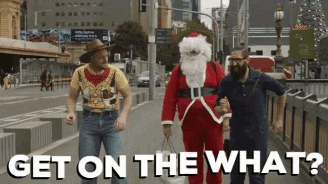 a man dressed as santa claus is walking down a street with two other men