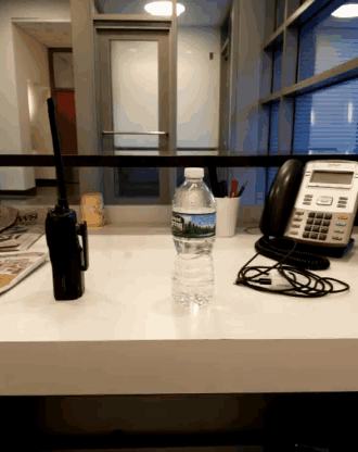 a bottle of water on a desk next to a walkie talkie
