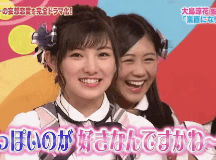 two girls are smiling in front of a colorful background with foreign writing on it