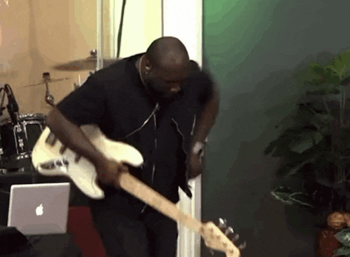 a man playing a guitar in front of a laptop