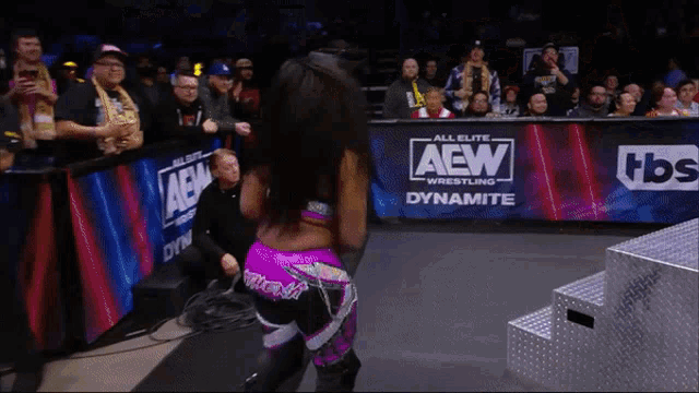 a woman stands in front of a aew sign