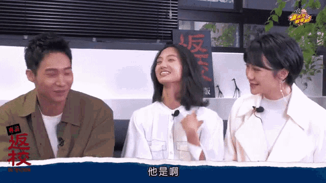 a man and two women are smiling in front of a sign that says ' hk ' on it