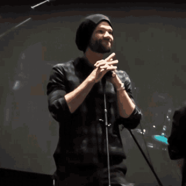 a man singing into a microphone wearing a beanie
