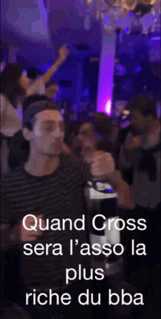 a man is holding a bottle of wine and says quand cross sera l ' asso la plus riche du bba