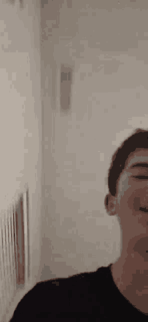 a young man in a black shirt is smiling in a bathroom .