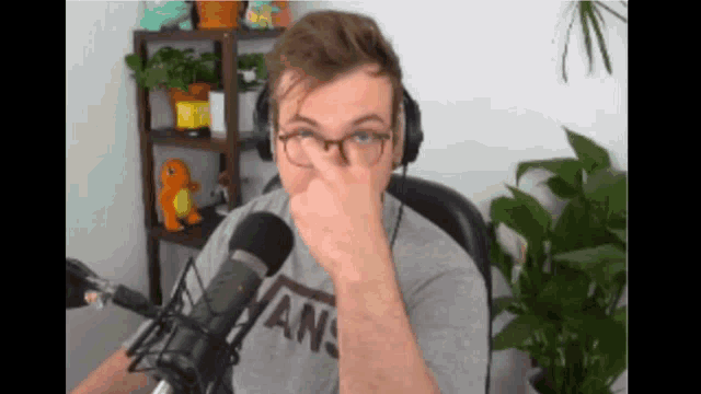a man wearing glasses and a vans shirt covering his nose