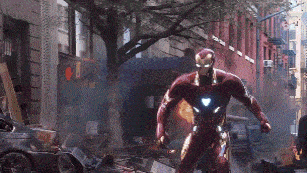 iron man is running down a city street in a superhero costume .