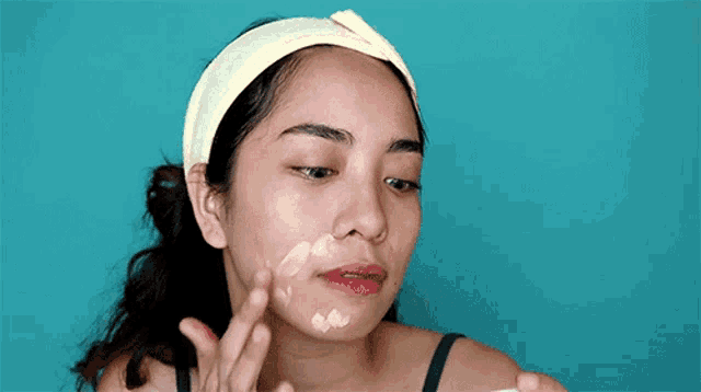 a woman is applying a cream to her face .