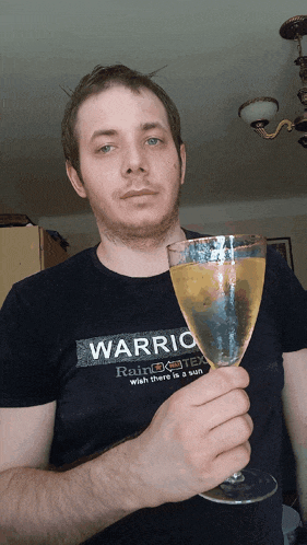 a man wearing a shirt that says warrio holds a glass of wine