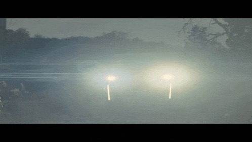 a car 's headlights are shining brightly in the dark
