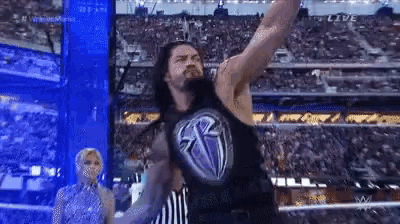 a wrestler is standing on a stage with his arms outstretched .