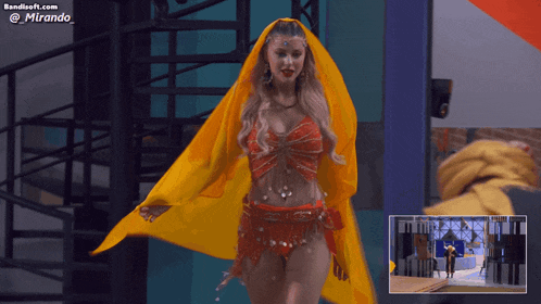 a woman in a red and yellow outfit is dancing in front of a banner that says bandsoft.com @mirando