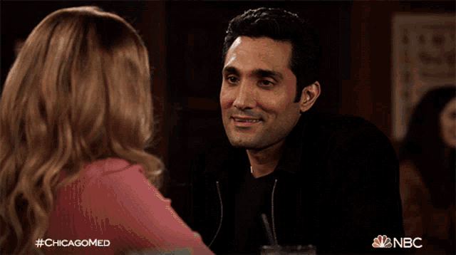 a man and a woman are sitting at a table with a nbc logo in the corner