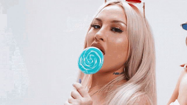 a woman wearing sunglasses holds a lollipop in her mouth