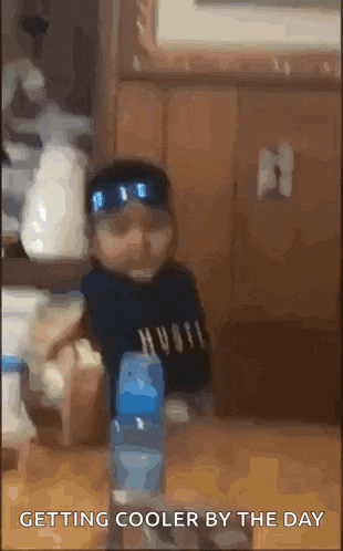 a baby is sitting at a table with a bottle of water in front of him .