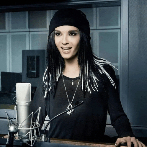 a woman wearing a black beanie is standing in front of a microphone and smiling