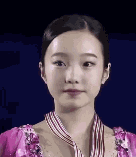 a close up of a young woman wearing a pink dress and a medal around her neck .