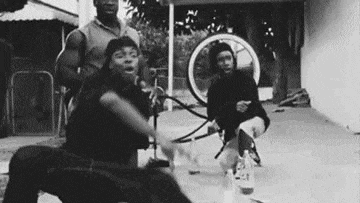 a black and white photo of a group of young men playing with a hula hoop .