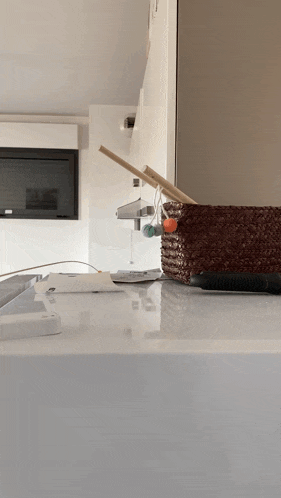 a remote control sits on a white counter next to a brown basket