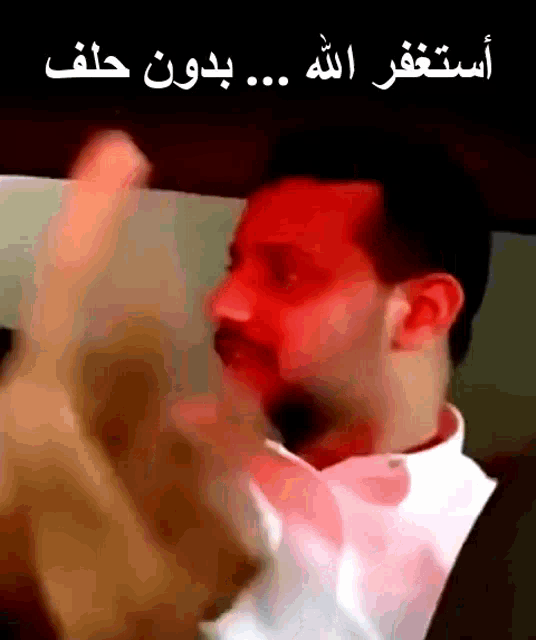 a man in a white shirt is making a funny face with arabic writing above him