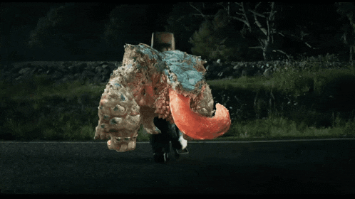 a car is driving down a road at night and a monster is flying overhead
