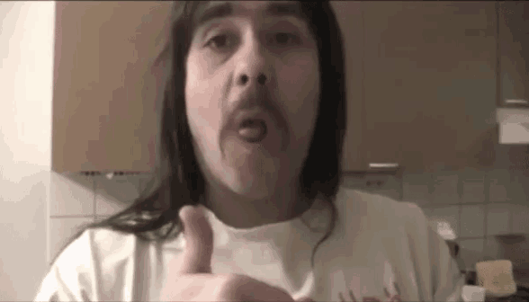 a man with long hair giving a thumbs up