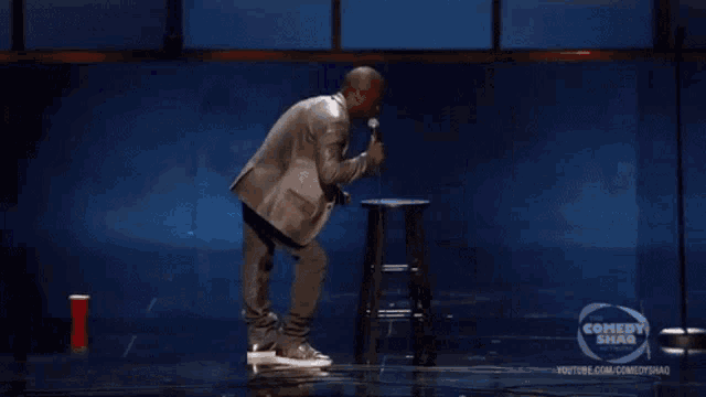 a man in a suit is playing a drum in front of a blue curtain that says youtube.com/comedyshao