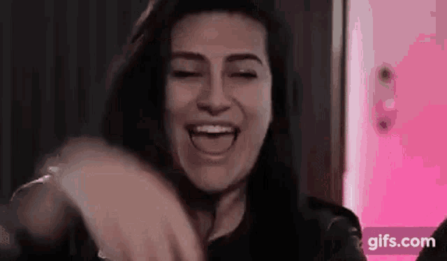 a woman is laughing with her mouth open and her eyes closed .