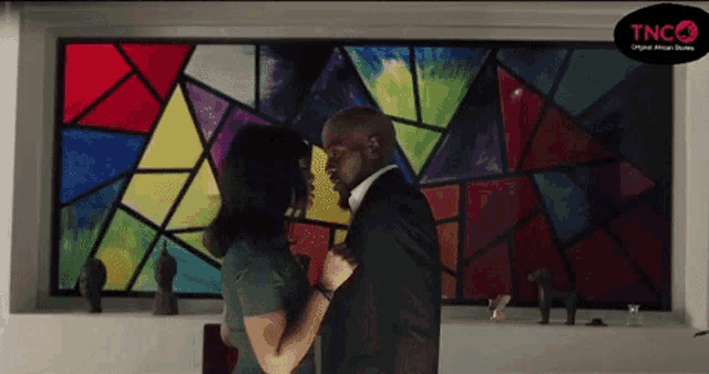 a man and a woman are kissing in front of a stained glass window that says tnco on it