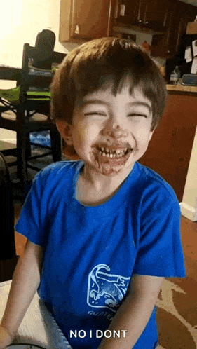 a young boy with chocolate on his face is smiling and making a face .