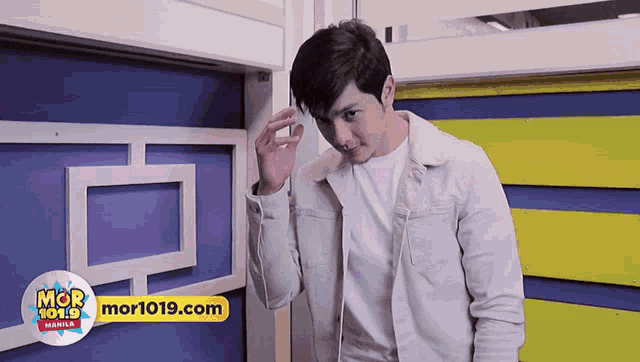 a man in a white jacket is standing in front of a sign that says mor 101.9