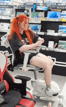 a woman with red hair is sitting on an exercise bike in a store