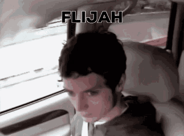 a man is sitting in the back seat of a car with the word flijah written above him