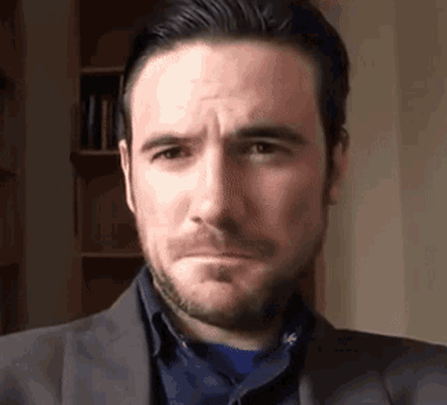 a man with a beard is wearing a suit and making a face