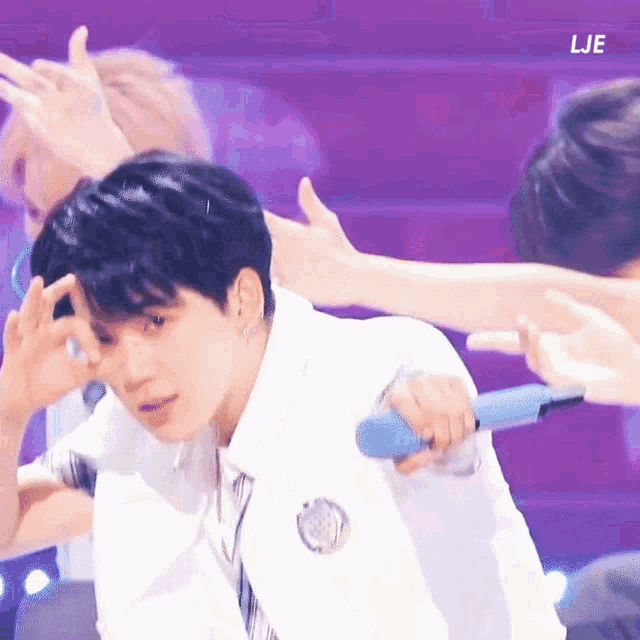 a man in a white shirt and tie is holding a blue microphone while dancing on a stage .