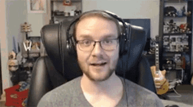 a man wearing glasses and headphones is sitting in a chair in a room .